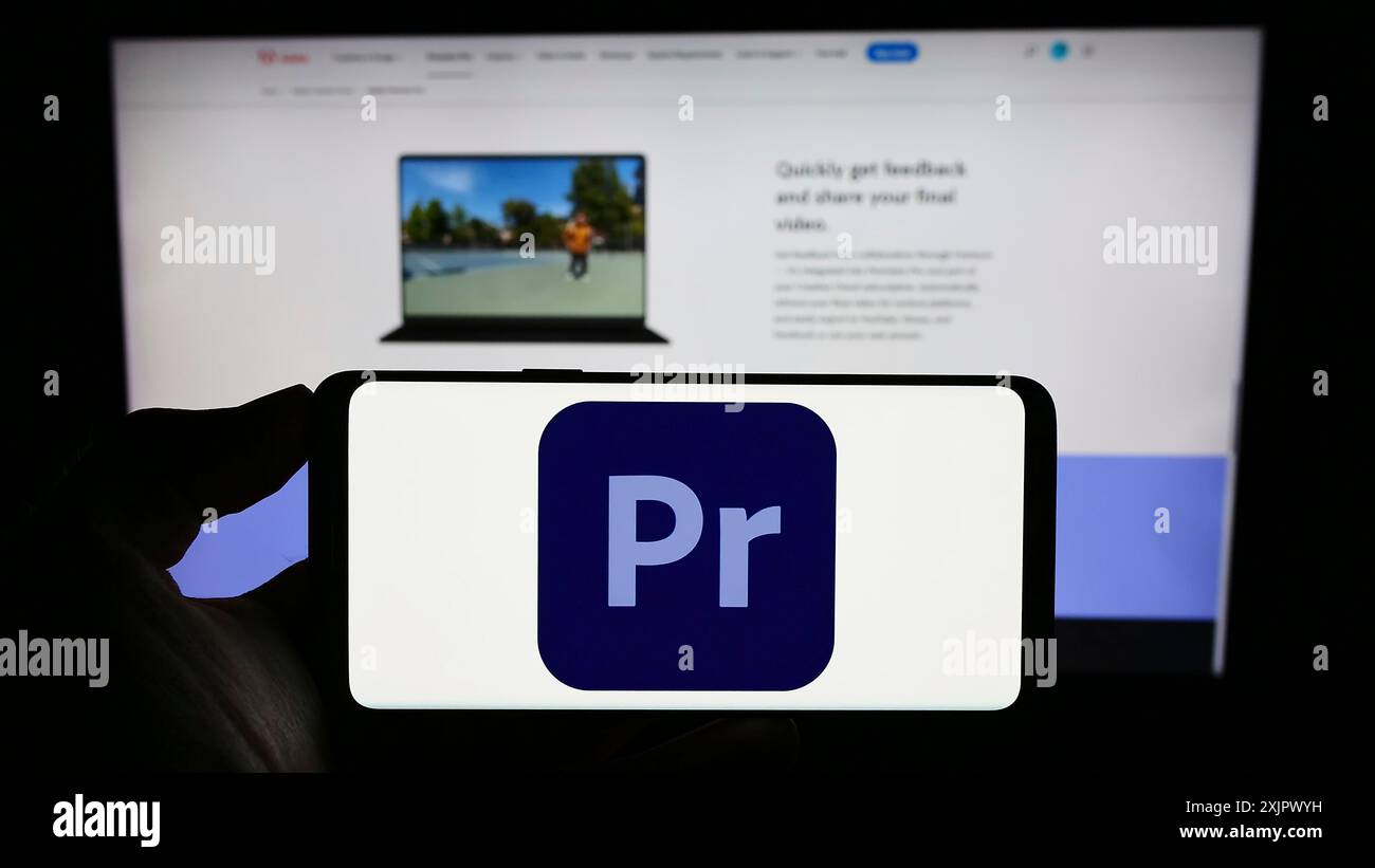 Stoccarda, Germania, 09-23-2023: Persona che tiene il cellulare con il logo del software di editing video Adobe Premiere Pro sullo schermo di fronte all'azienda Foto Stock