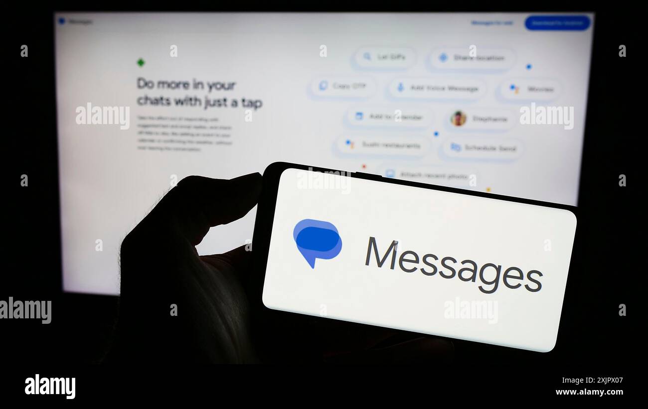 Stoccarda, Germania, 09-23-2023: Persona che tiene un cellulare con il logo dell'app di messaggistica istantanea messaggi di Google sullo schermo di fronte alla pagina Web dell'azienda. Foto Stock