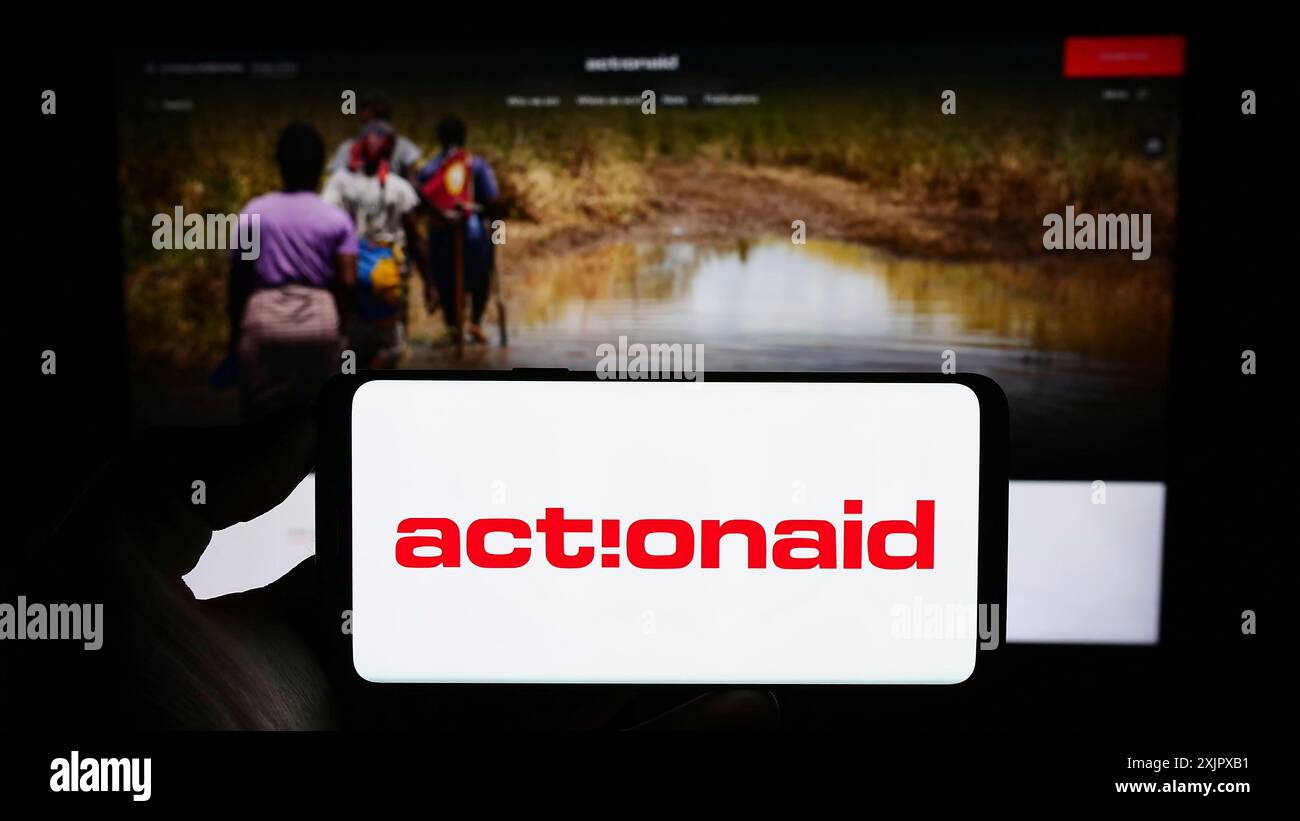 Stoccarda, Germania, 10-08-2023: Persona che detiene un telefono cellulare con il logo dell'organizzazione benefica internazionale ActionAid davanti alla pagina web. Concentrati su Foto Stock