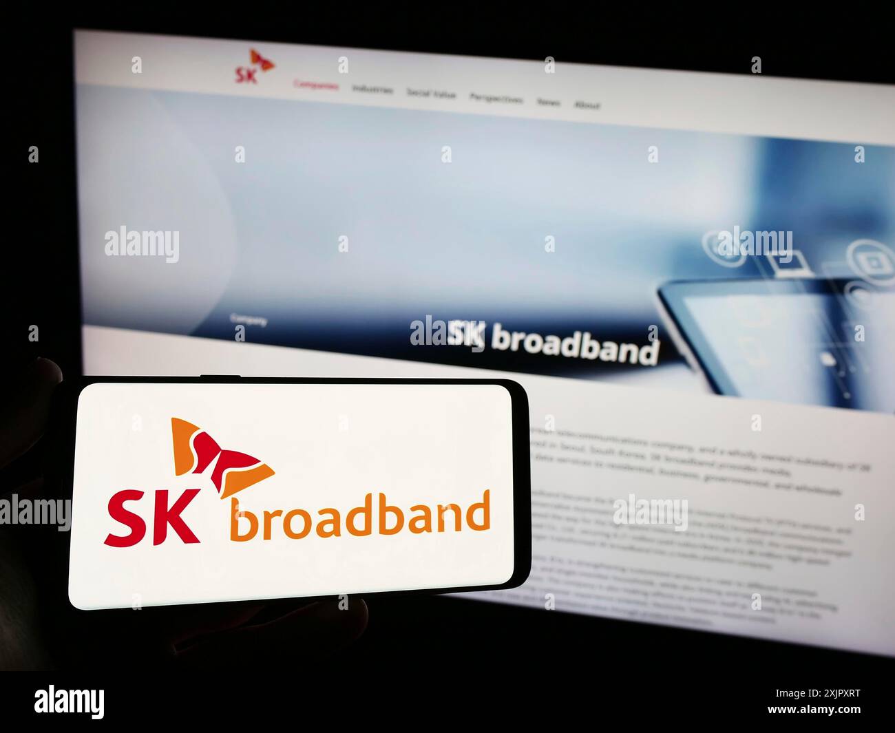 Stoccarda, Germania, 10-16-2023: Persona con smartphone con logo della società di telecomunicazioni coreana SK Broadband Inc. Davanti al sito web. Concentrati Foto Stock