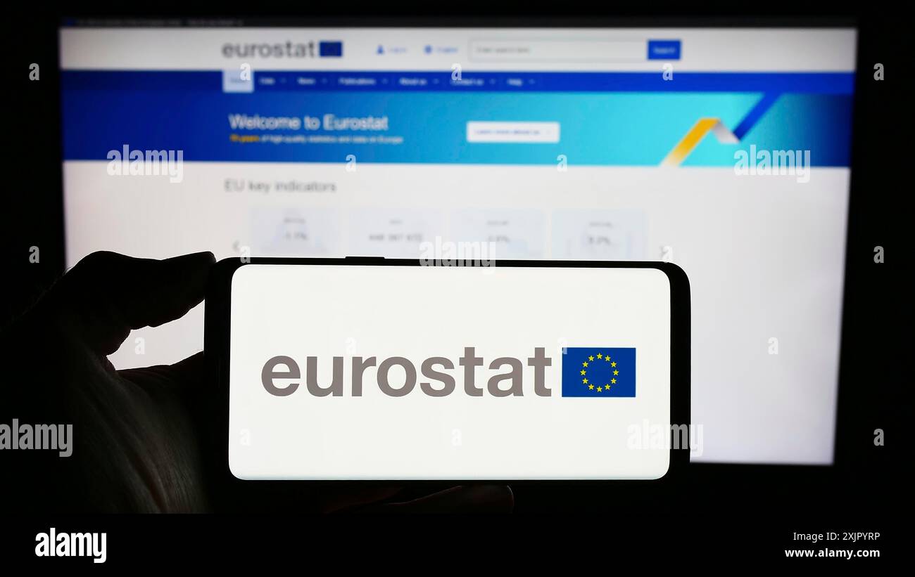 Stoccarda, Germania, 11-02-2023: Persona che detiene il cellulare con il logo dell’Istituto europeo di statistica Eurostat di fronte all’impresa Foto Stock