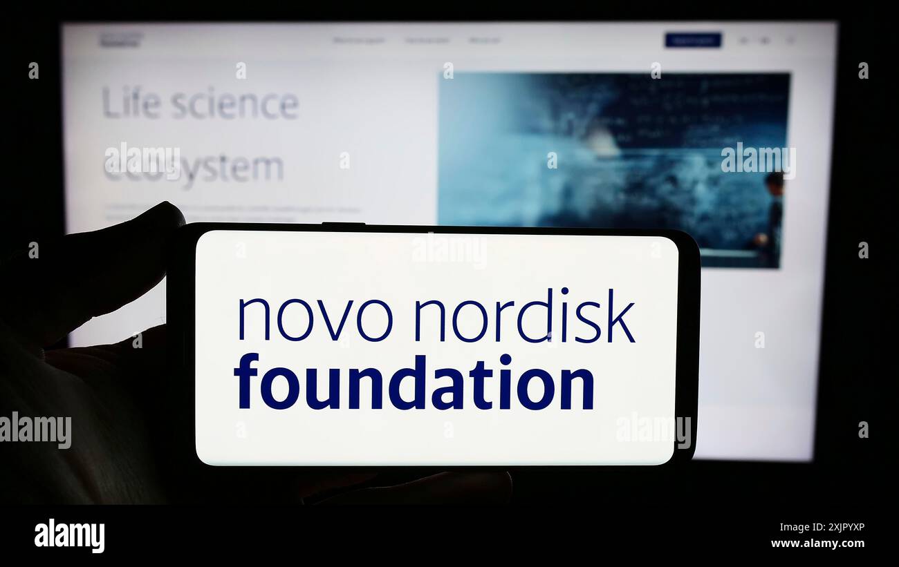 Stoccarda, Germania, 11-02-2023: Persona con smartphone con logo dell'organizzazione danese Novo Nordisk Foundation davanti al sito web. Concentrati su Foto Stock