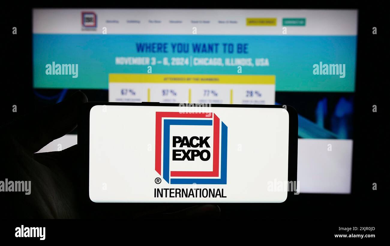 Stoccarda, Germania, 11-10-2023: Persona con smartphone con logo della fiera statunitense PACK EXPO International davanti al sito Web. Concentrati sul telefono Foto Stock