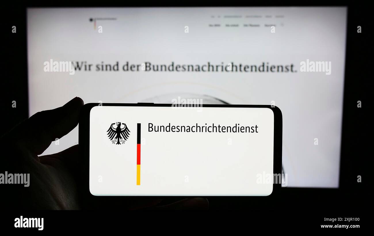 Stoccarda, Germania, 11-11-2023: Persona con smartphone e logo dell'agenzia di intelligence tedesca Bundesnachrichtendienst (BND) davanti al sito web. Foto Stock