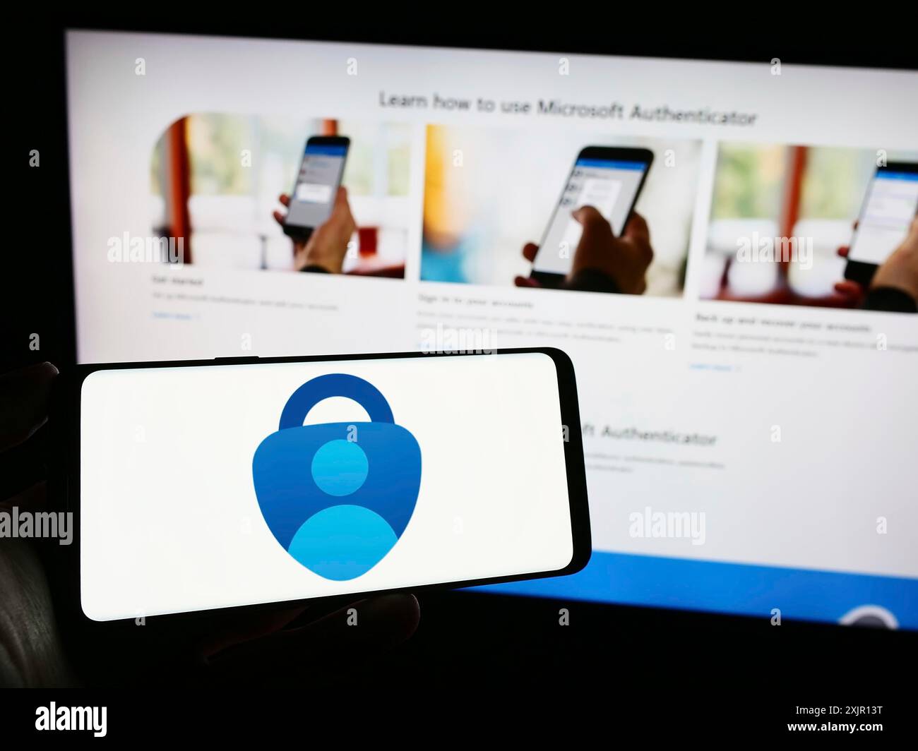 Stoccarda, Germania, 11-14-2023: Persona che detiene un cellulare con il logo dell'app di autenticazione Microsoft Authenticator di fronte alla pagina Web dell'azienda. Concentrati Foto Stock