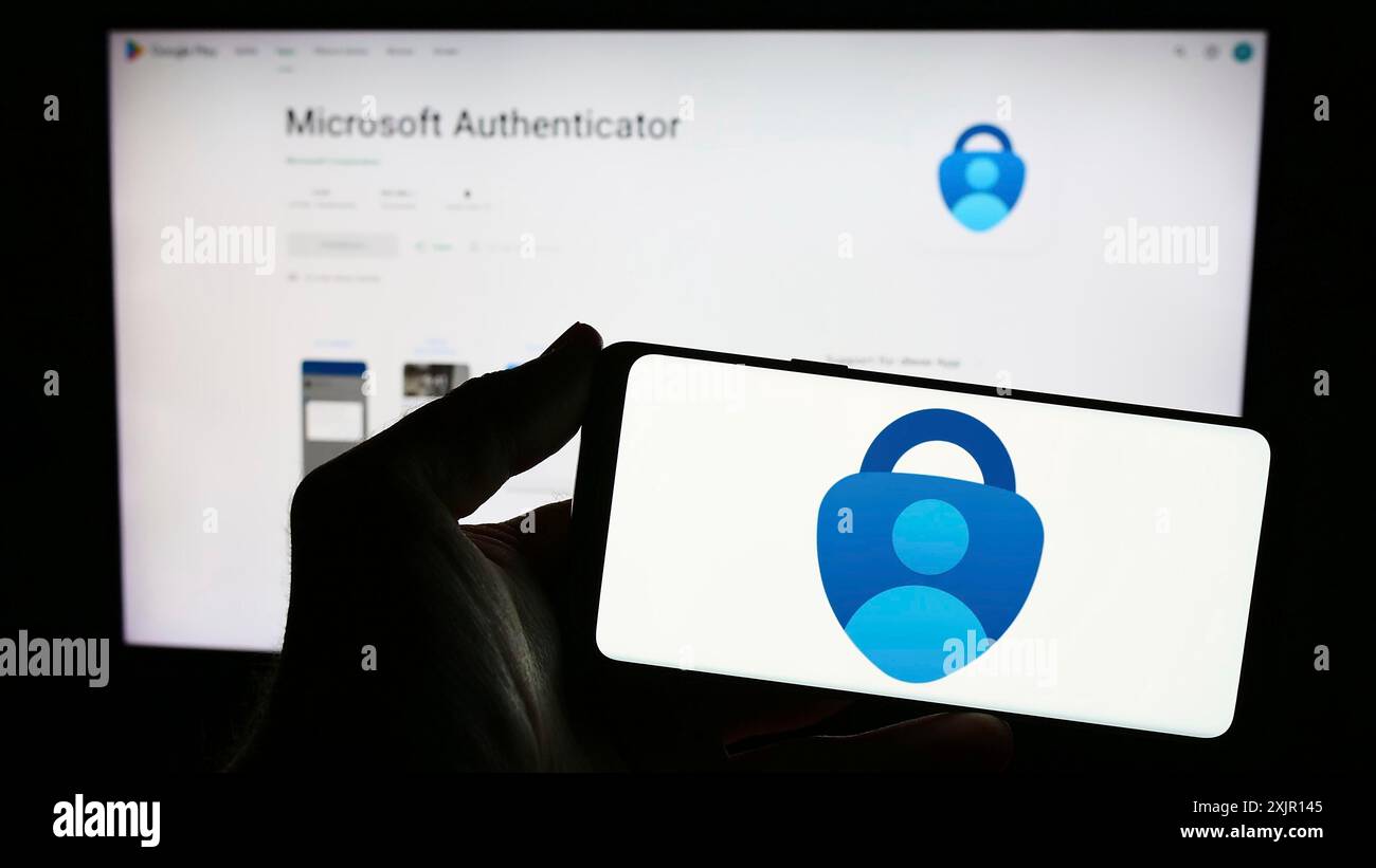 Stoccarda, Germania, 11-14-2023: Persona con smartphone con logo dell'app di autenticazione Microsoft Authenticator davanti al sito Web. Concentrati sul telefono Foto Stock