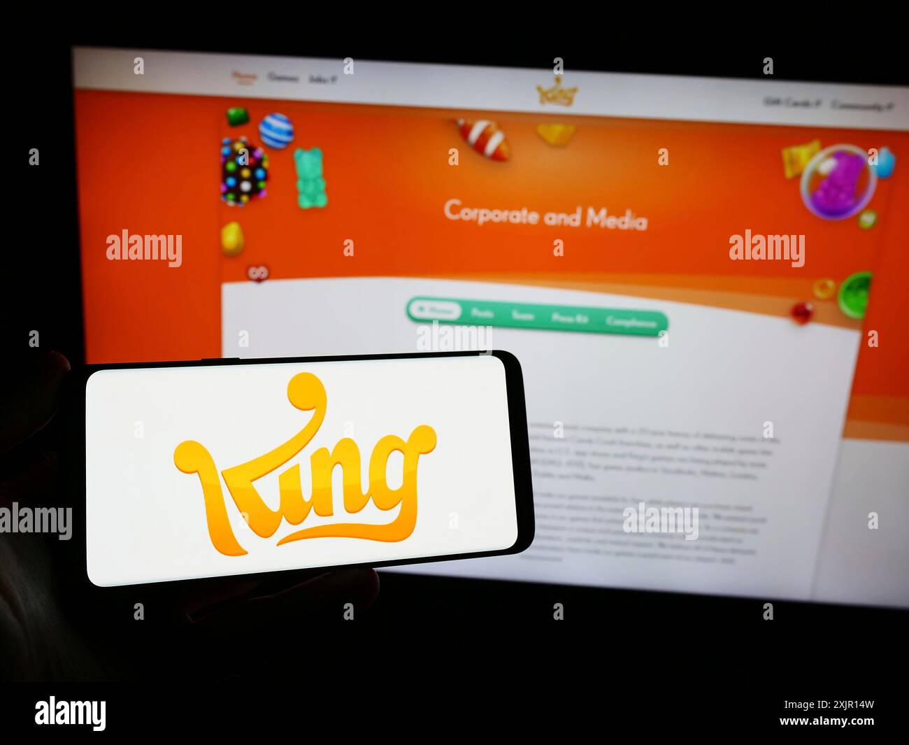 Stoccarda, Germania, 11-14-2023: Persona con smartphone con logo della società svedese di sviluppo di videogiochi King.com Limited davanti al sito web. Foto Stock