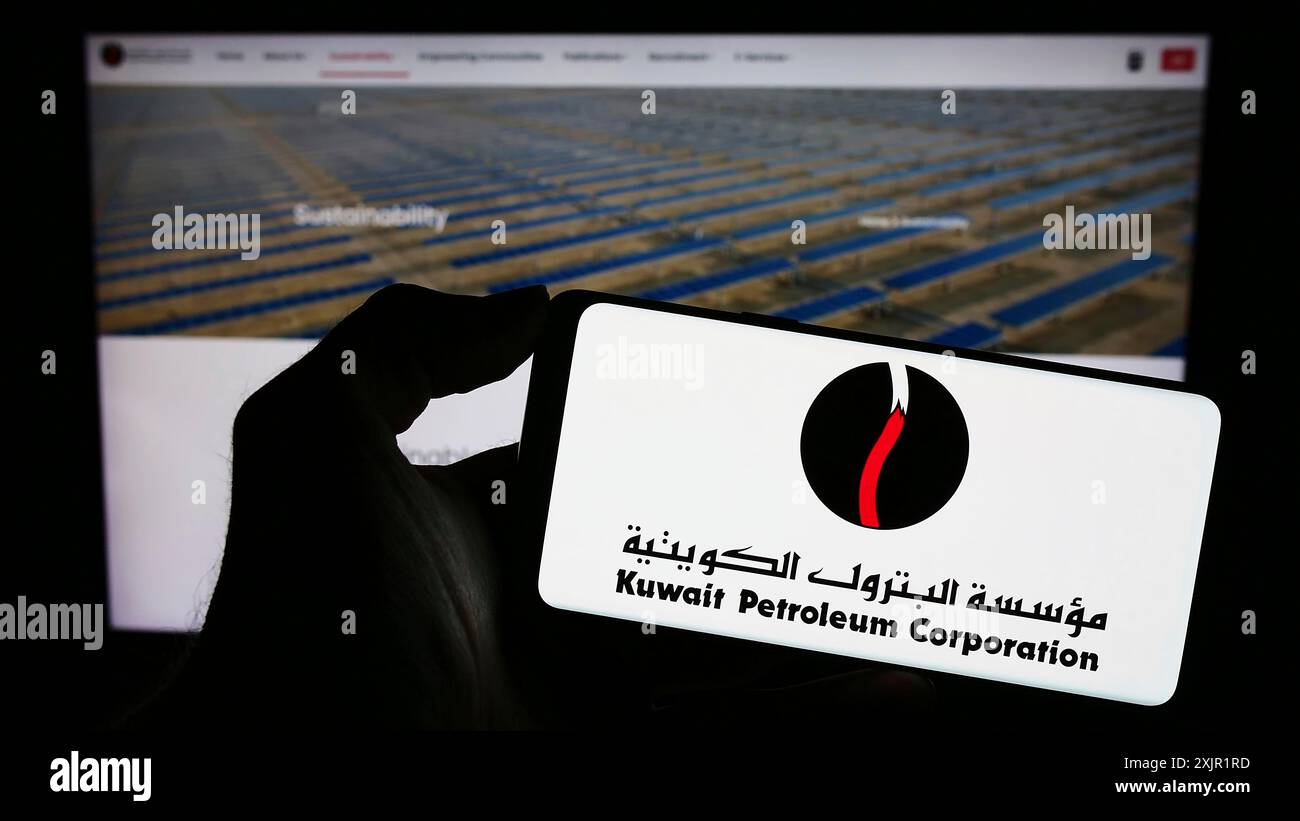 Stoccarda, Germania, 11-23-2023: Persona che detiene il cellulare con il logo della società petrolifera kuwaitiana Kuwait Petroleum Corporation (KPC) di fronte alla pagina web. Foto Stock