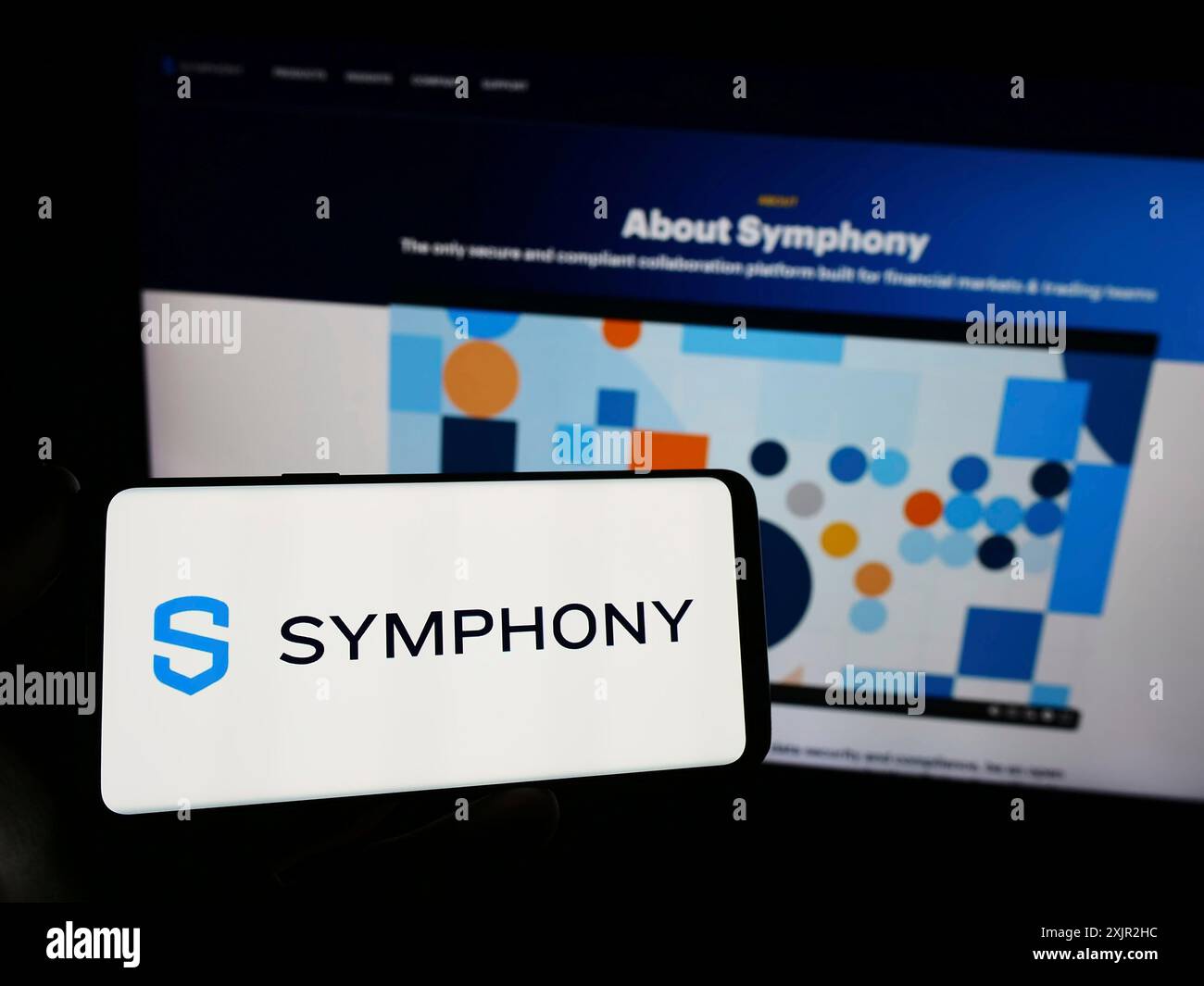 Stoccarda, Germania, 12-07-2023: Persona con smartphone con logo della società di messaggistica statunitense Symphony Communication Services LLC davanti al sito web. Foto Stock