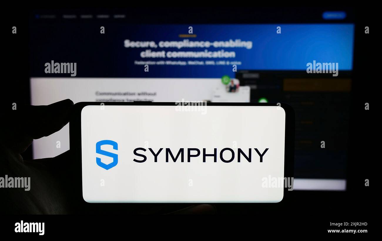 Stoccarda, Germania, 12-07-2023: Persona che detiene un telefono cellulare con il logo della società di messaggistica statunitense Symphony Communication Services LLC davanti al web Foto Stock