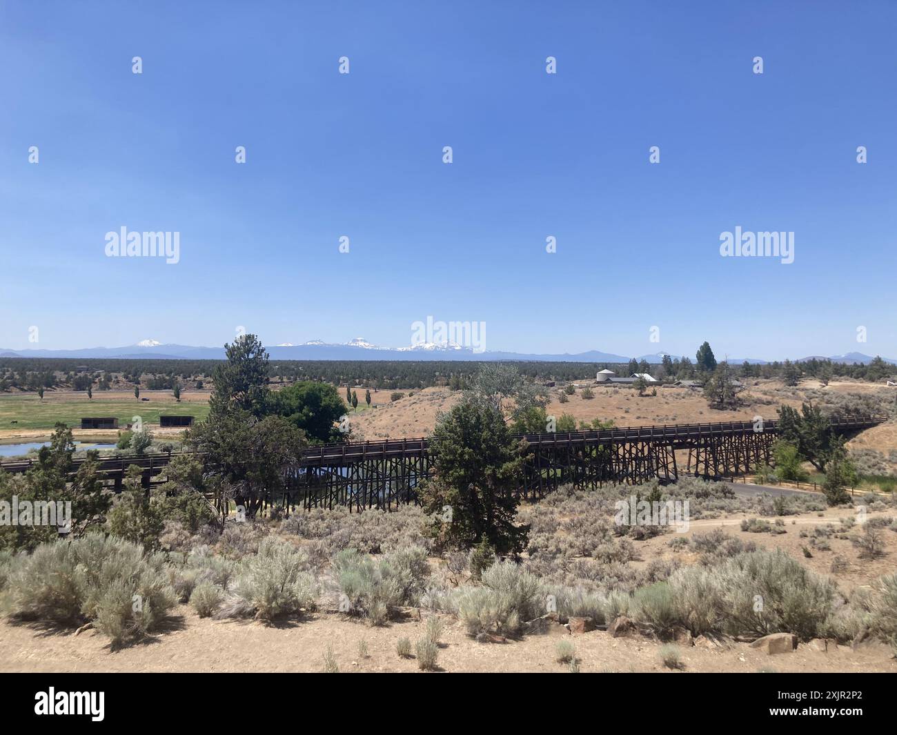 Vista su un ponte di cavalletti al Brasada Ranch, un resort di lusso vicino a Bend, verso le montagne Sisters in Oregon. Foto Stock