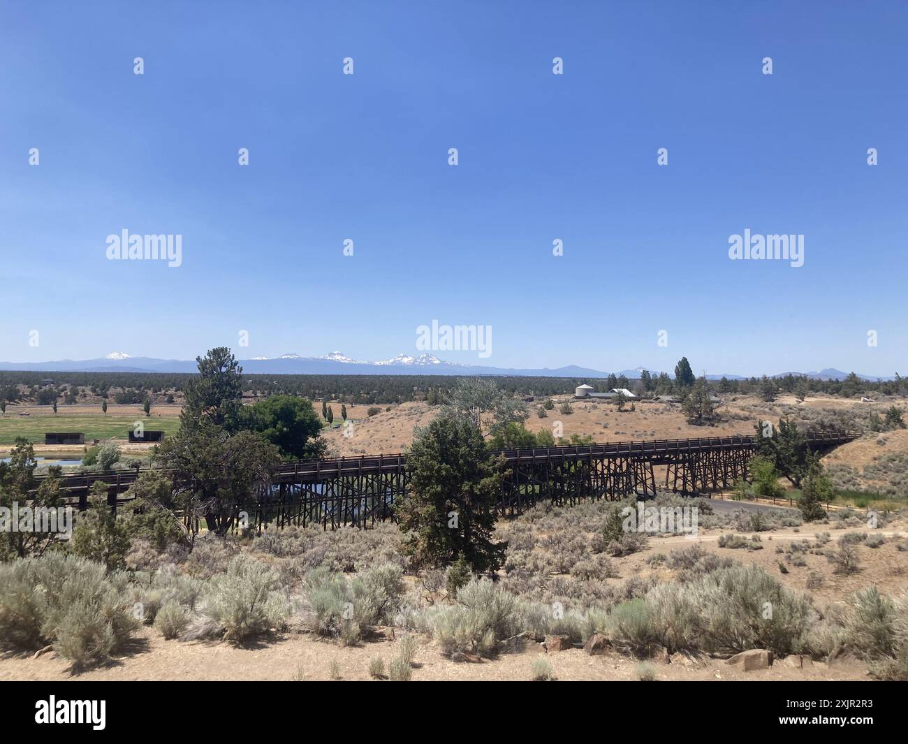 Vista su un ponte di cavalletti al Brasada Ranch, un resort di lusso vicino a Bend, verso le montagne Sisters in Oregon. Foto Stock
