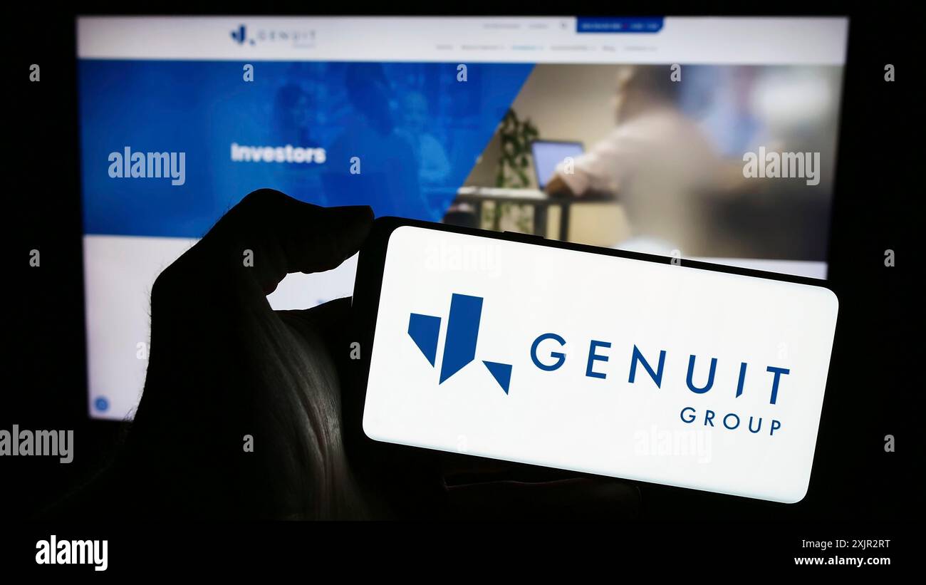 Stoccarda, Germania, 12-12-2023: Persona che detiene un telefono cellulare con il logo della società britannica di sistemi di tubazioni Genuit Group plc di fronte al web aziendale Foto Stock