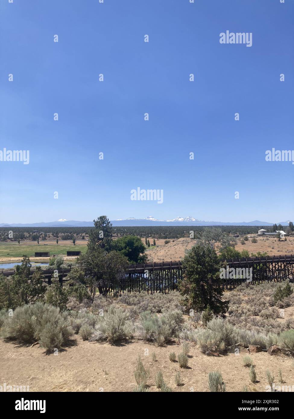 Vista su un ponte di cavalletti al Brasada Ranch, un resort di lusso vicino a Bend, verso le montagne Sisters in Oregon. Foto Stock