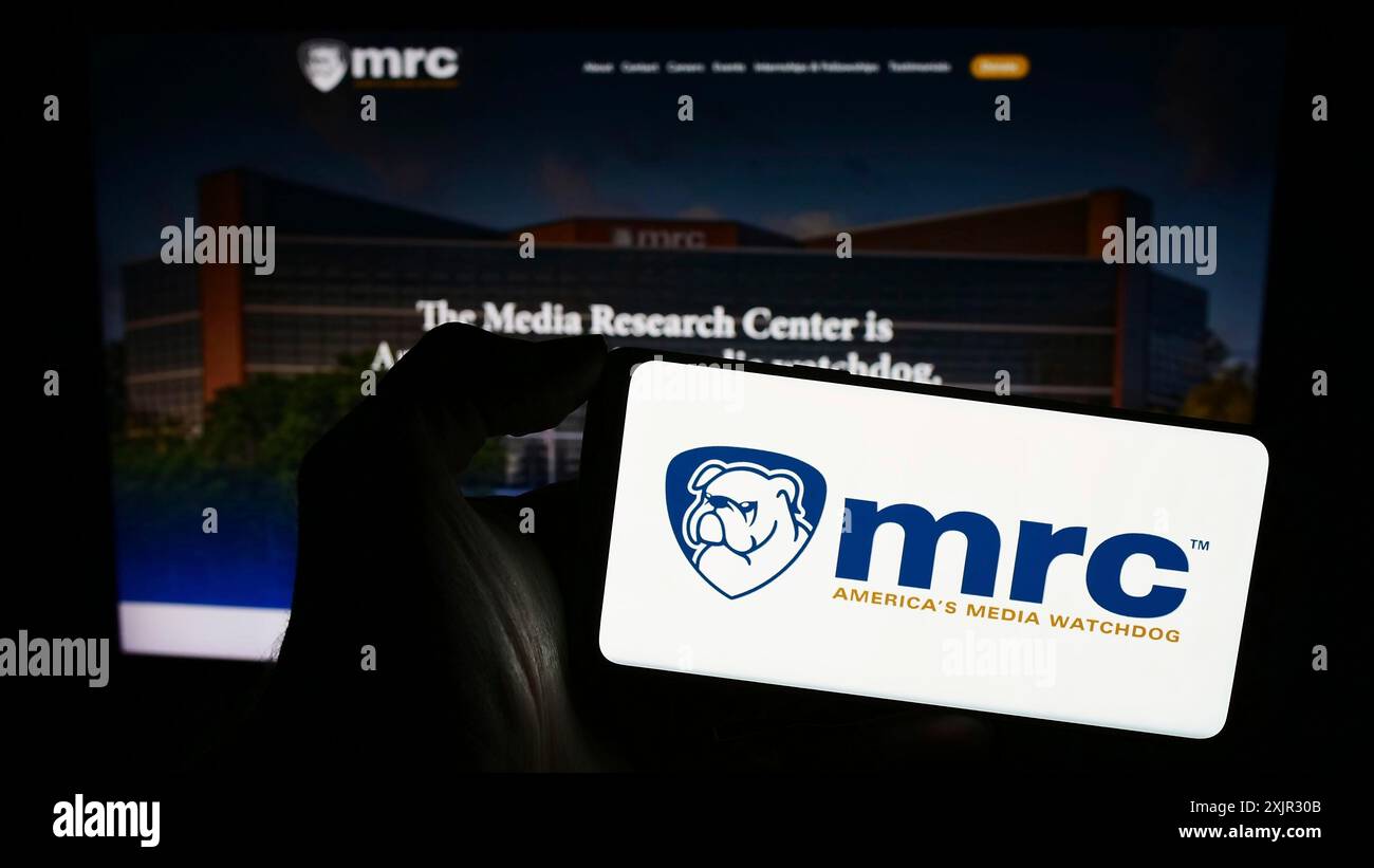 Stoccarda, Germania, 12-14-2023: Persona che tiene un telefono cellulare con il logo dell'organizzazione di controllo Media Research Center (MRC) di fronte alla pagina web. Foto Stock