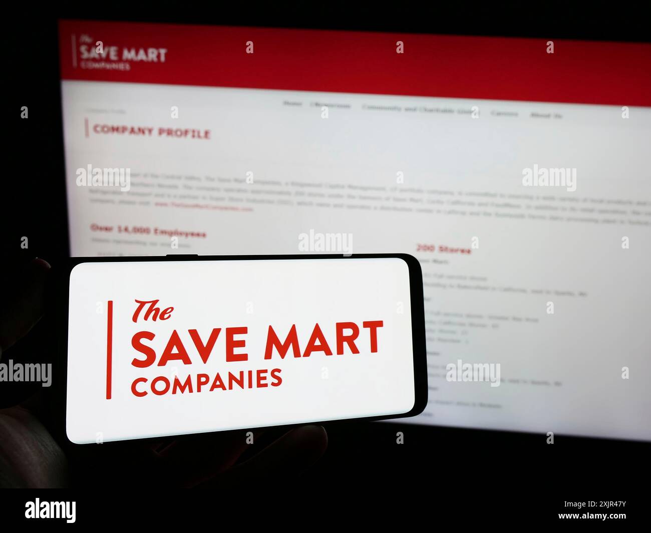 Stoccarda, Germania, 02-03-2024: Persona che detiene un telefono cellulare con il logo della società americana di supermercati The Save Mart Companies davanti alla pagina web. Foto Stock