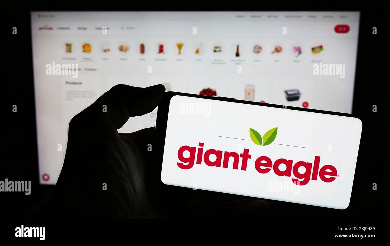 Stuttgart, Germania, 02-03-2024: Persona che detiene un telefono cellulare con il logo della catena di supermercati americana Giant Eagle Inc. Davanti alla pagina web. Foto Stock