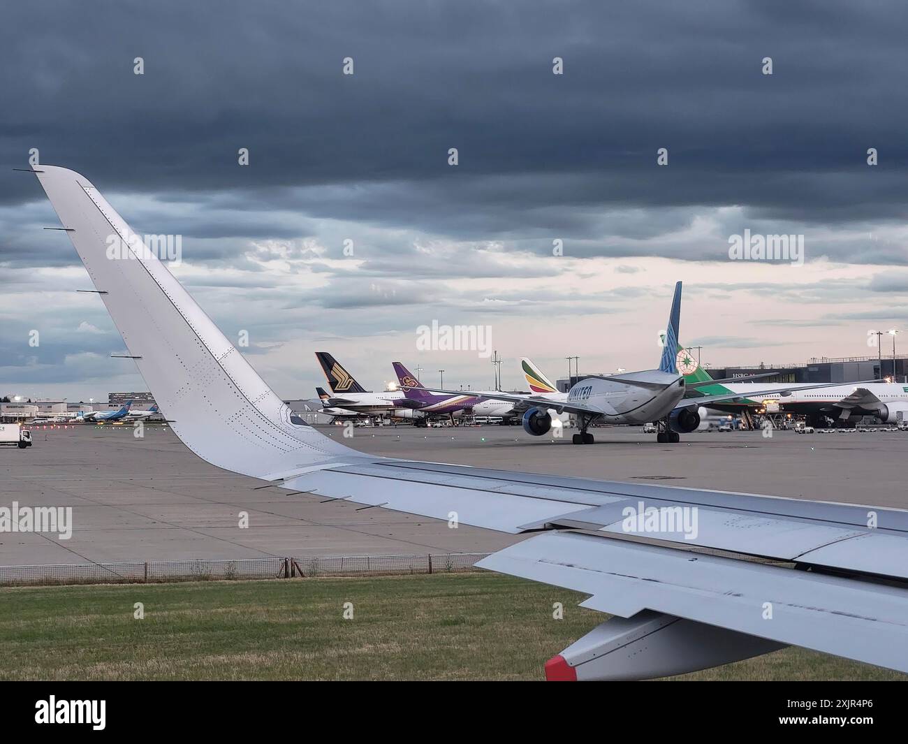 Aerei al Terminal 2 dell'Aeroporto Heathrow di Londra in una giornata nuvolosa Foto Stock