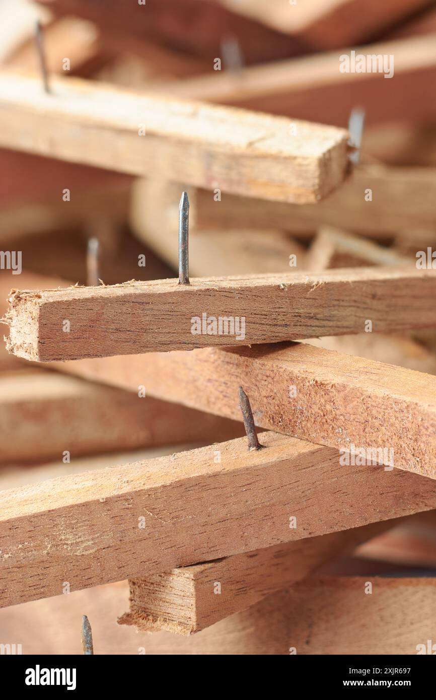 primo piano di pezzi di legno raschiati con chiodi sporgenti, lasciati da progetti di costruzione o demolizione, rischio di lesioni e concetto di sicurezza Foto Stock