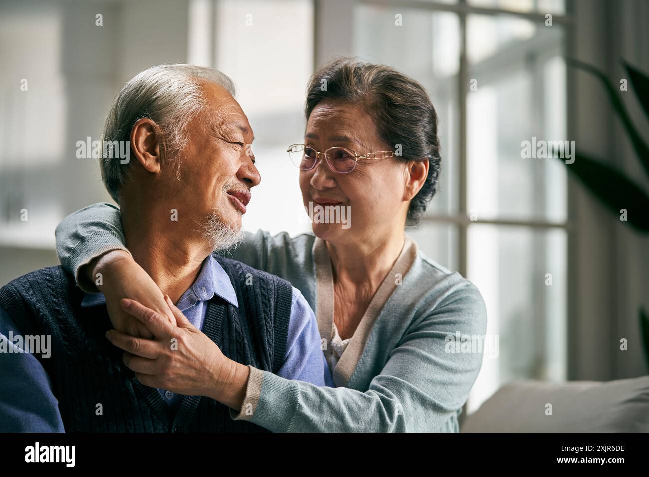 ritratto di una coppia asiatica senior felice e amorevole seduta sul divano a casa Foto Stock