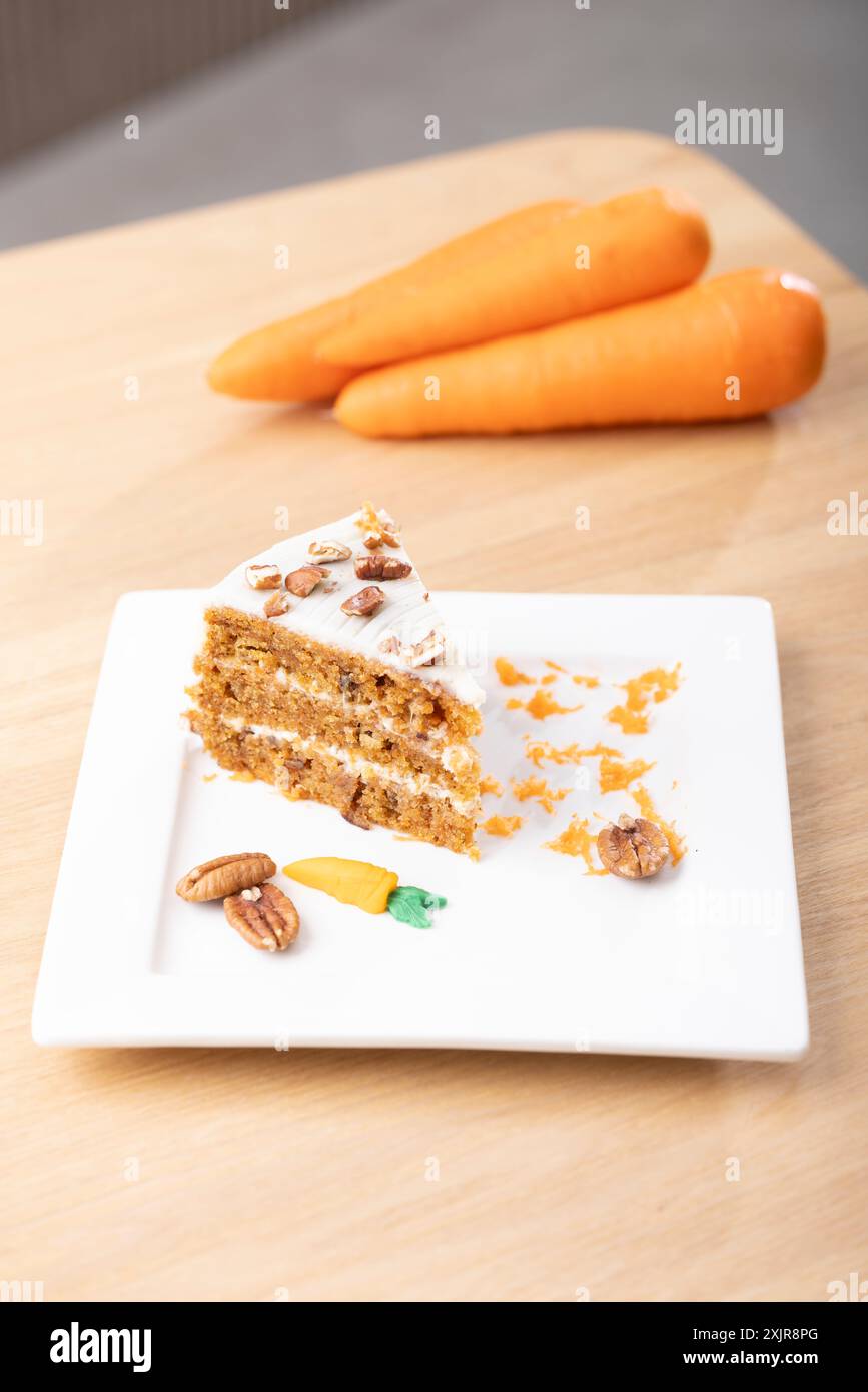 Deliziosa fetta di torta alla carota con glassa al formaggio. Un succulento primo piano di una fetta di torta di carote con ricca glassa di formaggio spalmabile. Foto Stock