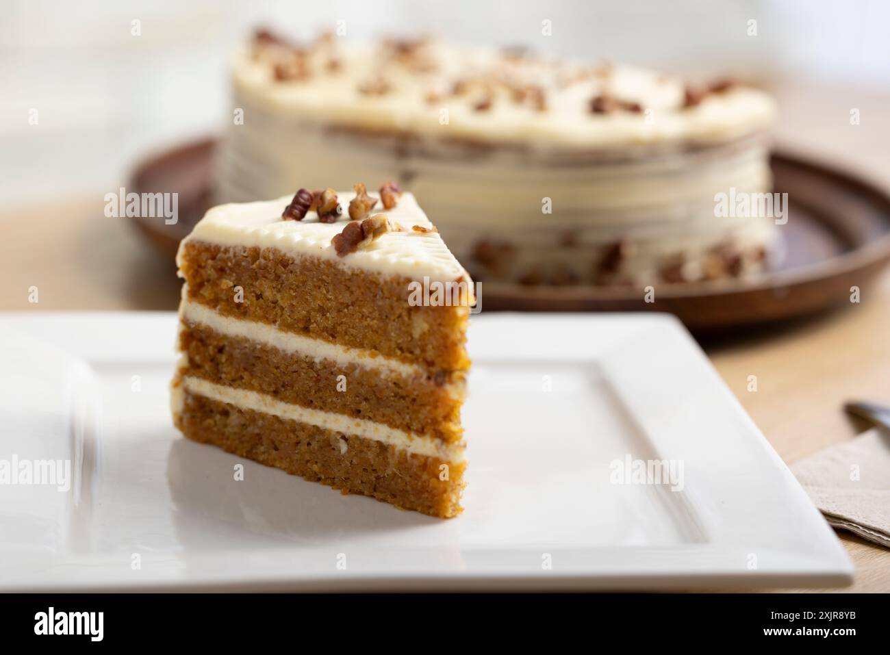 Deliziosa fetta di torta alla carota con glassa al formaggio. Un succulento primo piano di una fetta di torta di carote con ricca glassa di formaggio spalmabile. Foto Stock