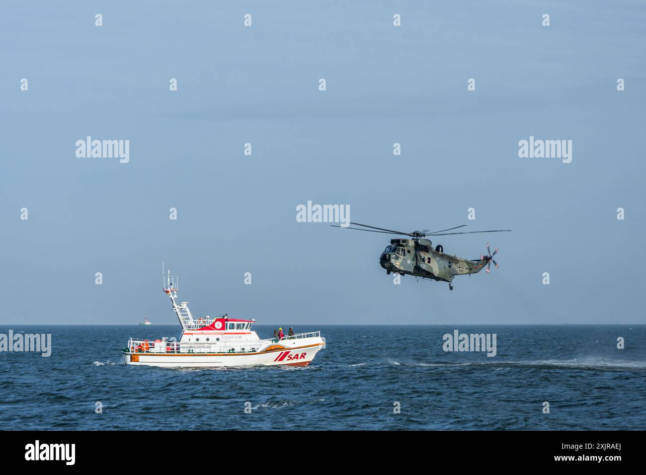 Incrociatore di salvataggio SAR nel Mare del Nord con un elicottero della Marina tedesca che sorvola l'acqua Foto Stock