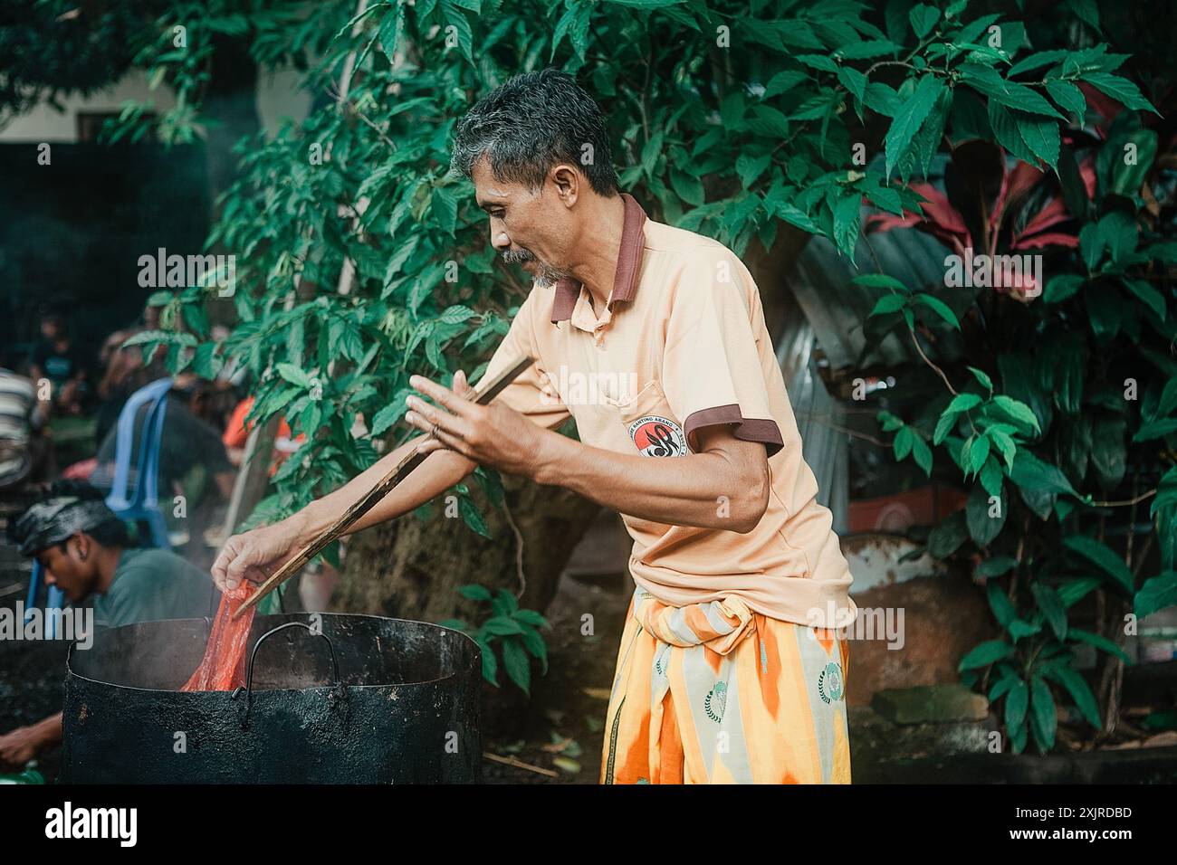 Un uomo balinese in un sarong prepara il cibo prima di una cerimonia a Bali, Indonesia, il 9 gennaio 2015 Foto Stock