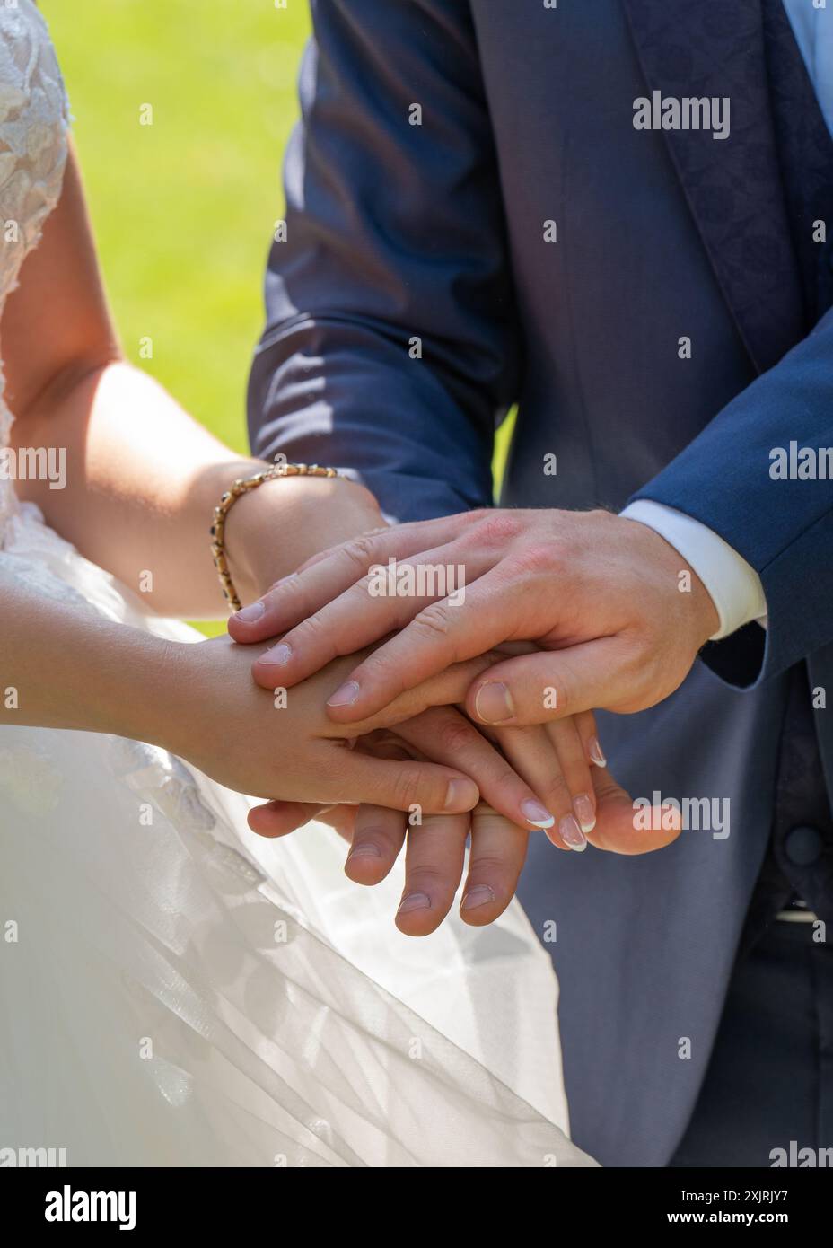 La sposa e lo sposo si tengono per mano durante le promesse. La mano del testimone e' sopra. Le mani della sposa e dello sposo sono da vicino. Foto Stock