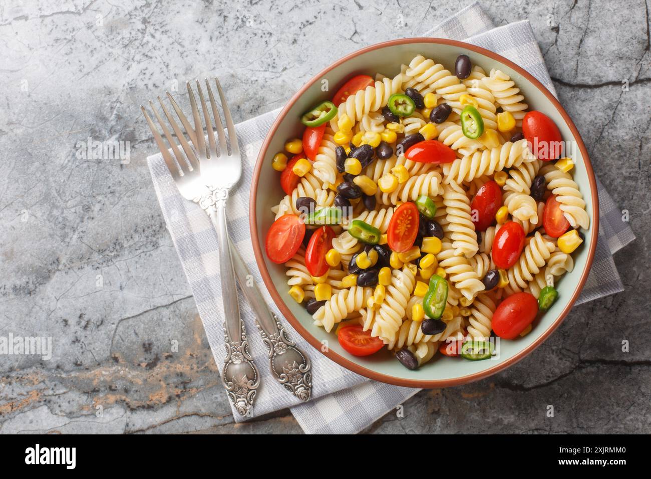 Insalata di pasta fresca fatta in casa con fusilli vegani con fagioli, mais, pomodoro e jalapeno in un piatto sul tavolo. Vista dall'alto orizzontale da abo Foto Stock