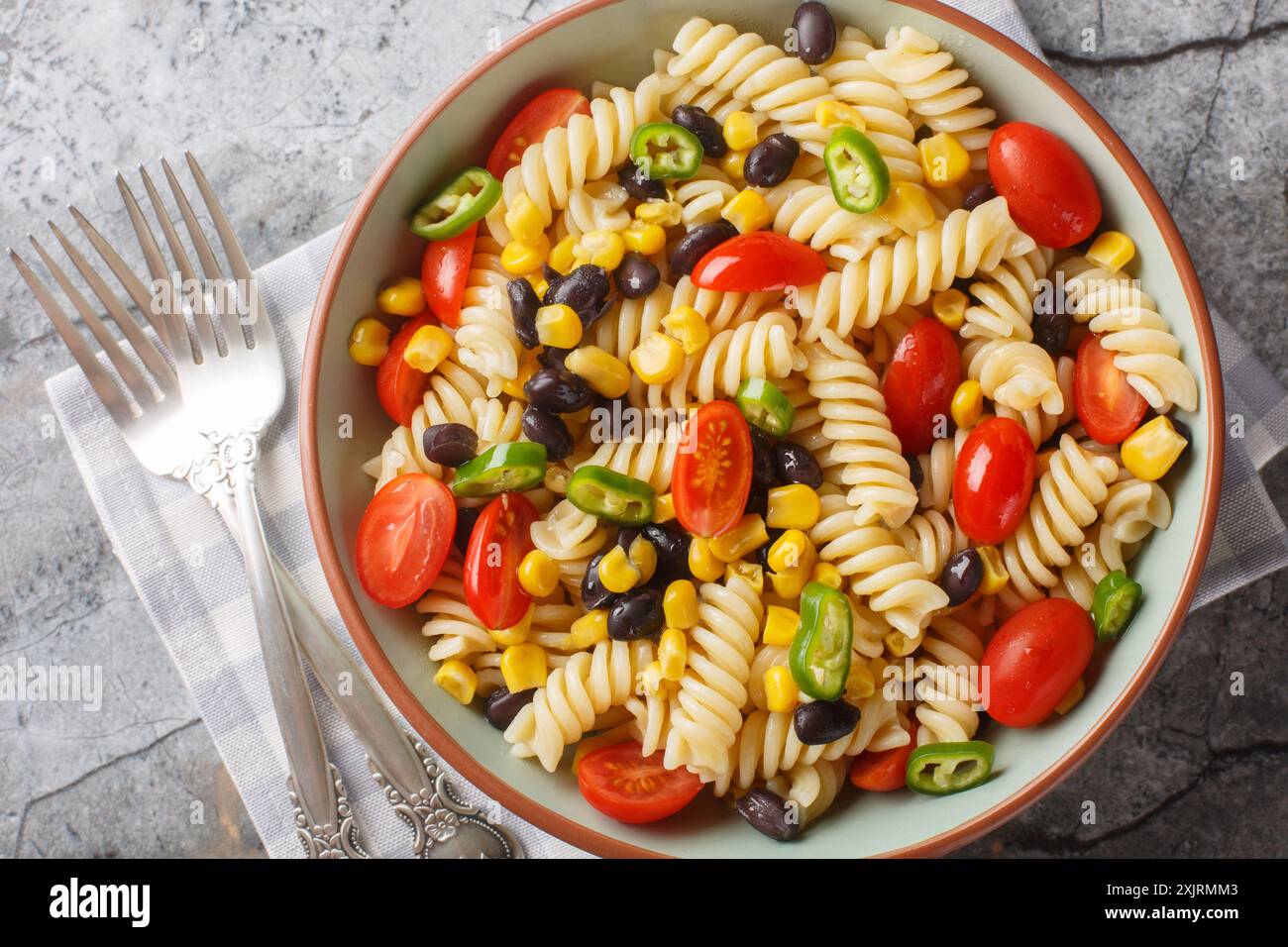Fusilli con fagioli neri, pomodoro, jalapeno e mais in primo piano in un piatto sul tavolo. Vista dall'alto orizzontale Foto Stock