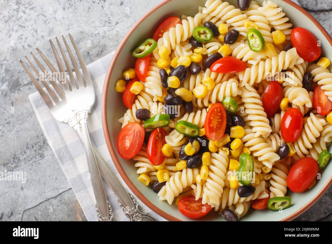 insalata semplice e sostanziosa di fusilli, fagioli neri, pomodori e mais da vicino in un piatto sul tavolo. Vista dall'alto orizzontale Foto Stock