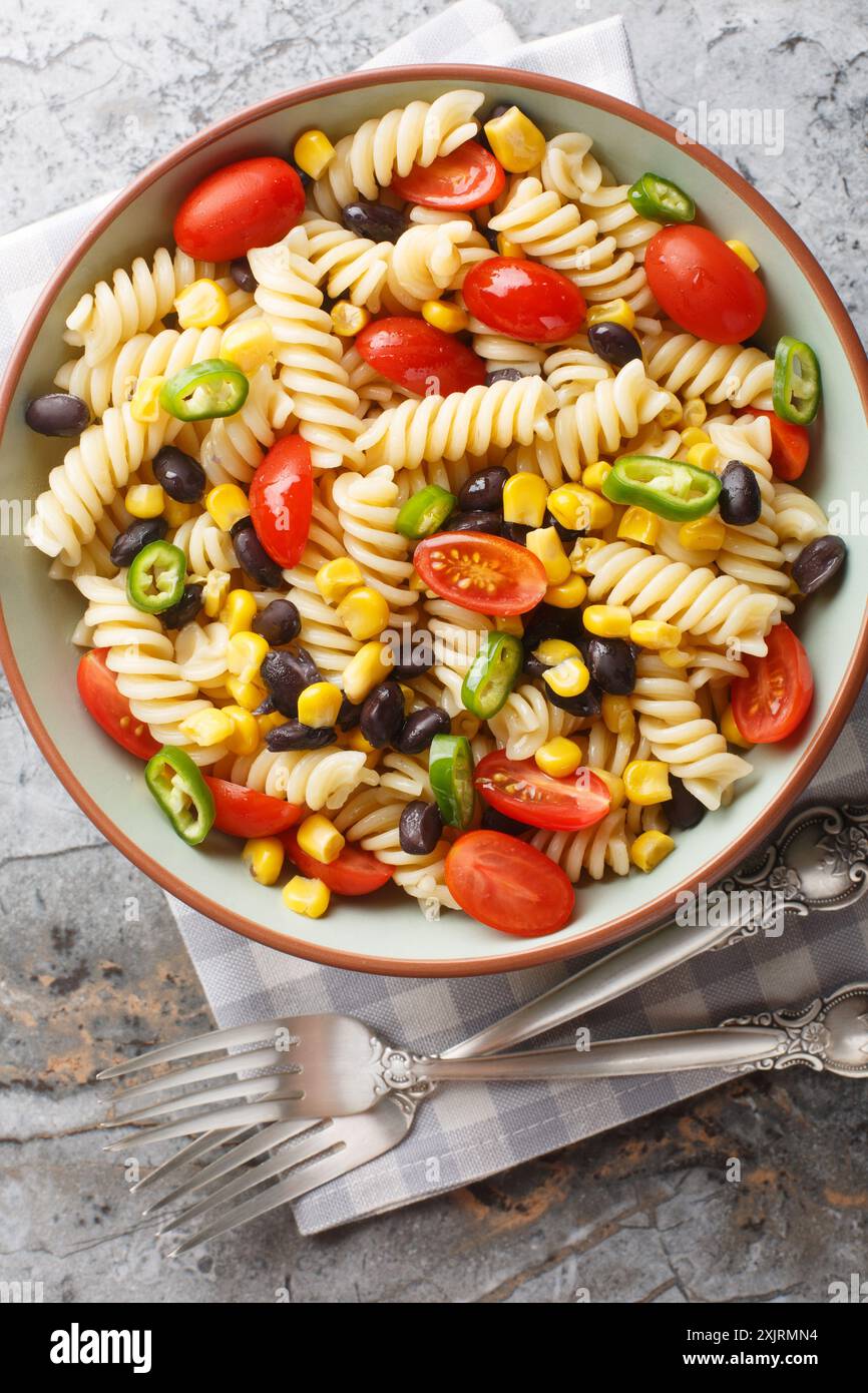 Insalata vegetariana di pasta messicana con fagioli neri, mais, pomodoro, cipolla e jalapeno in un piatto sul tavolo. Vista dall'alto verticale da abo Foto Stock