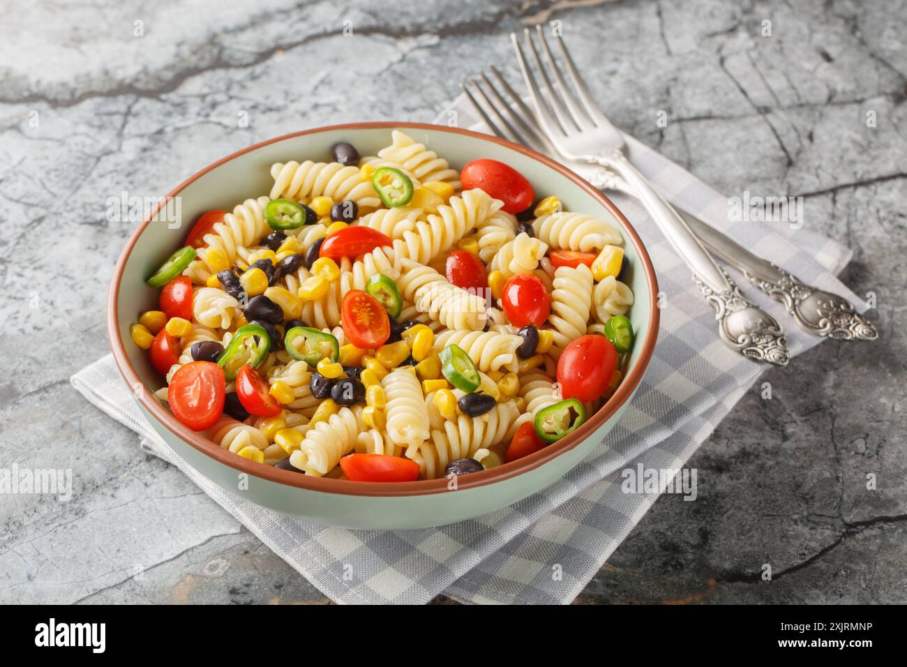 Insalata di pasta fresca fatta in casa con fusilli vegani con fagioli, mais, pomodoro e jalapeno in un piatto sul tavolo. Orizzontale Foto Stock