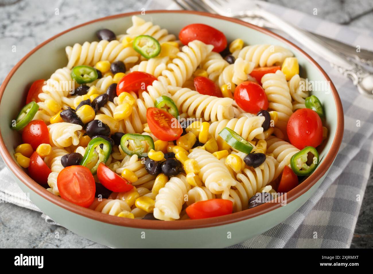 insalata semplice e sostanziosa di fusilli, fagioli neri, pomodori e mais da vicino in un piatto sul tavolo. Orizzontale Foto Stock