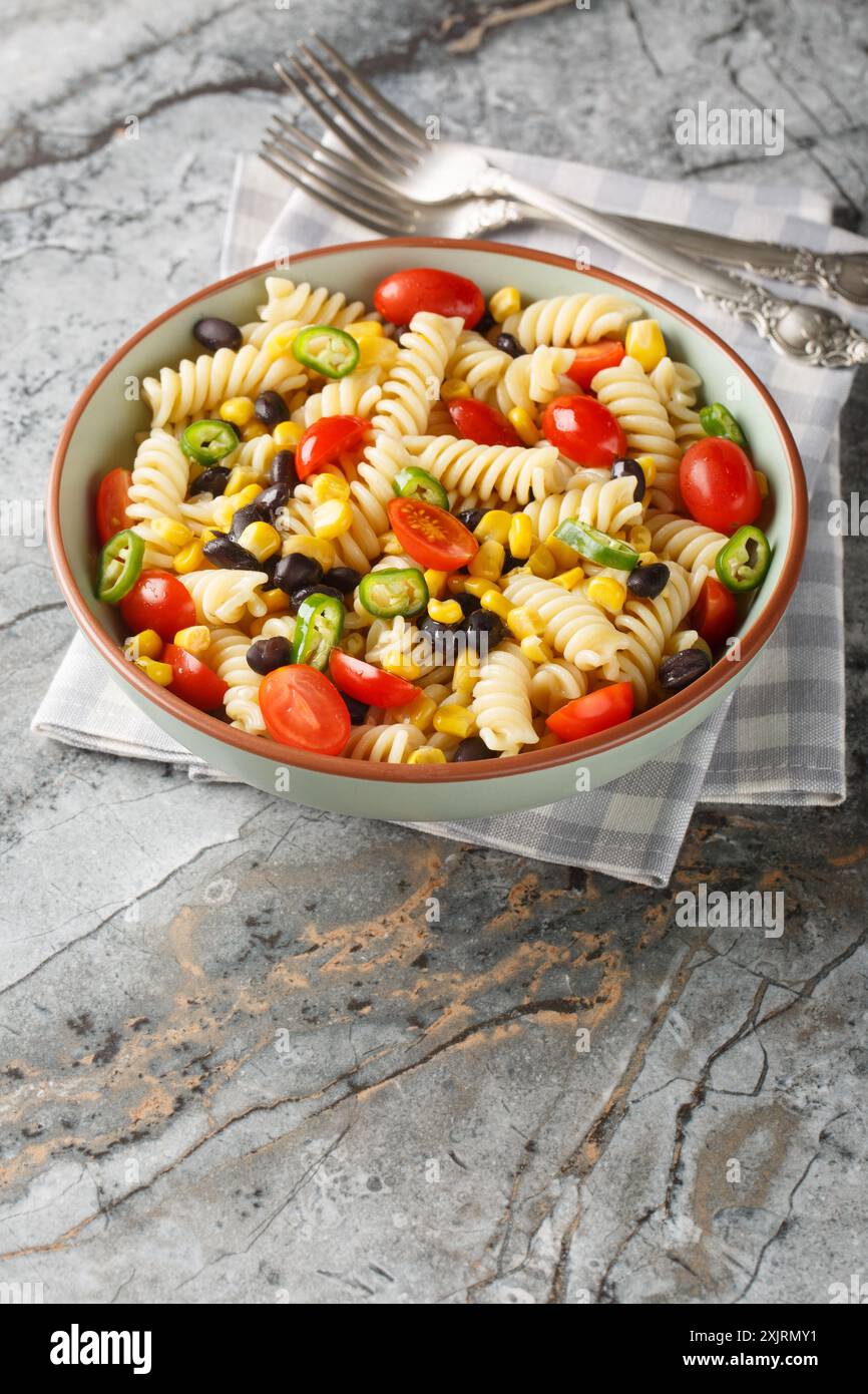 Insalata vegetariana di pasta messicana con fagioli neri, mais, pomodoro, cipolla e jalapeno in un piatto sul tavolo. Verticale Foto Stock