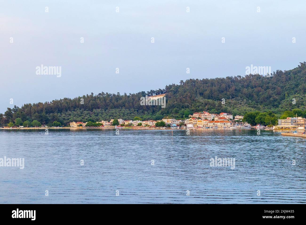 Vacanze estive in Grecia sullo sfondo con baia di acqua di mare e pini, vista del porto di Thassos e della città dal traghetto Foto Stock