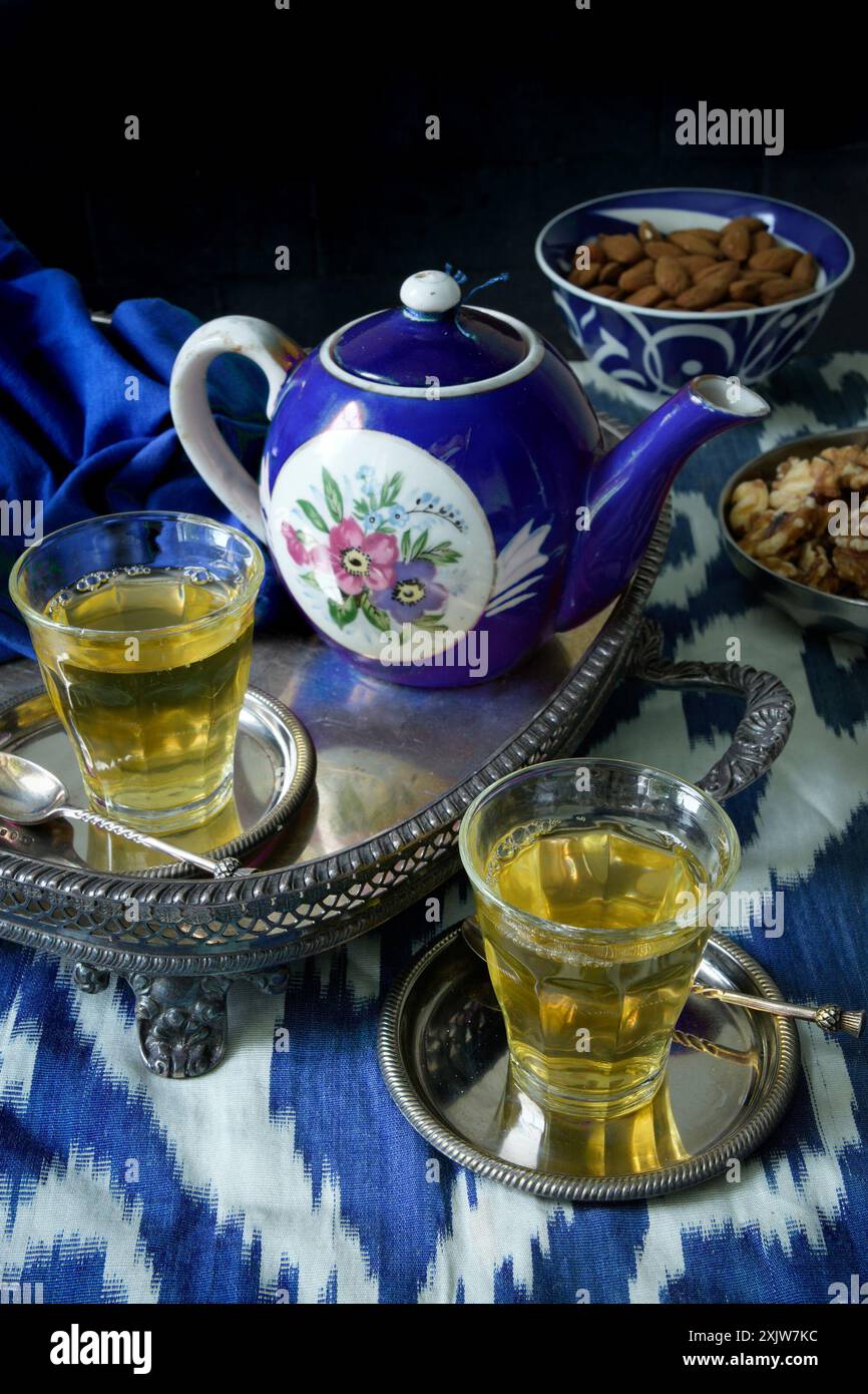 Due bicchieri di tè verde con una teiera russa di porcellana Gardner con glassa reale blu, su un vassoio d'argento antico, con materiale ikat blu e bianco Foto Stock