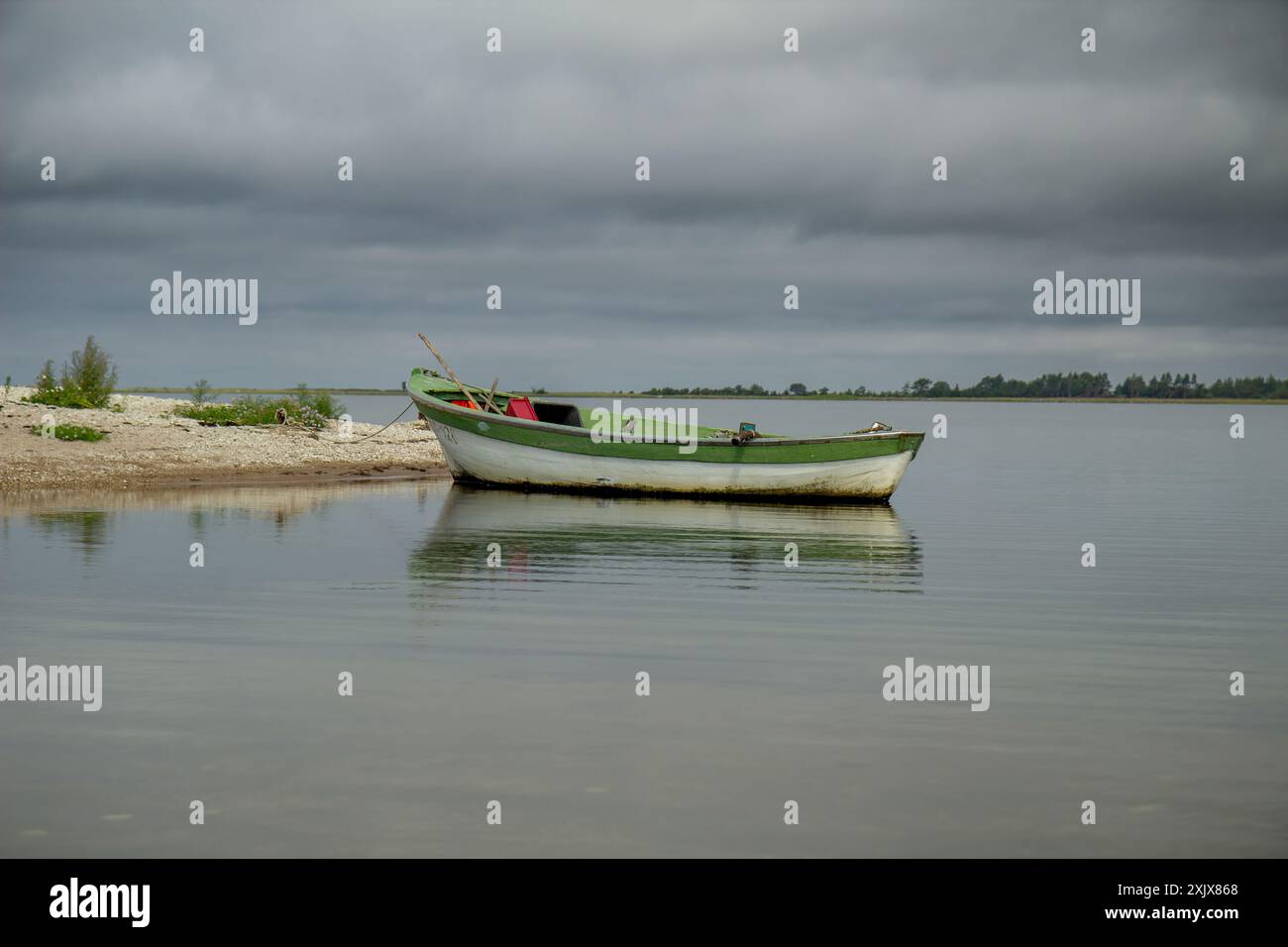 una barca da pesca solitaria attraccata in un mare calmo. barca da pesca in legno in acqua ferma. immagine di una barca da pesca in legno Foto Stock