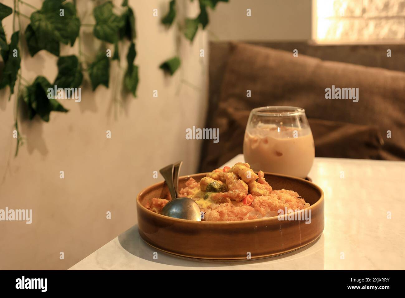 Riso di pollo con salsa di uova salate e spezie, Nasi Ayam Telur ASIN. Servito con caffè freddo. Atmosfera da caffetteria Foto Stock