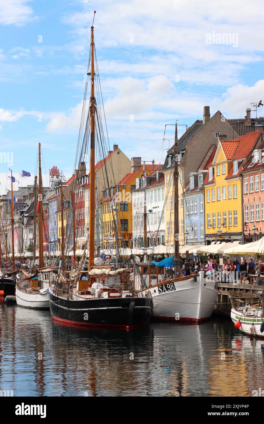 Case e barche colorate, che si riflettono sull'acqua, al porto di Nyhavn a Copenaghen, Danimarca, Europa Foto Stock