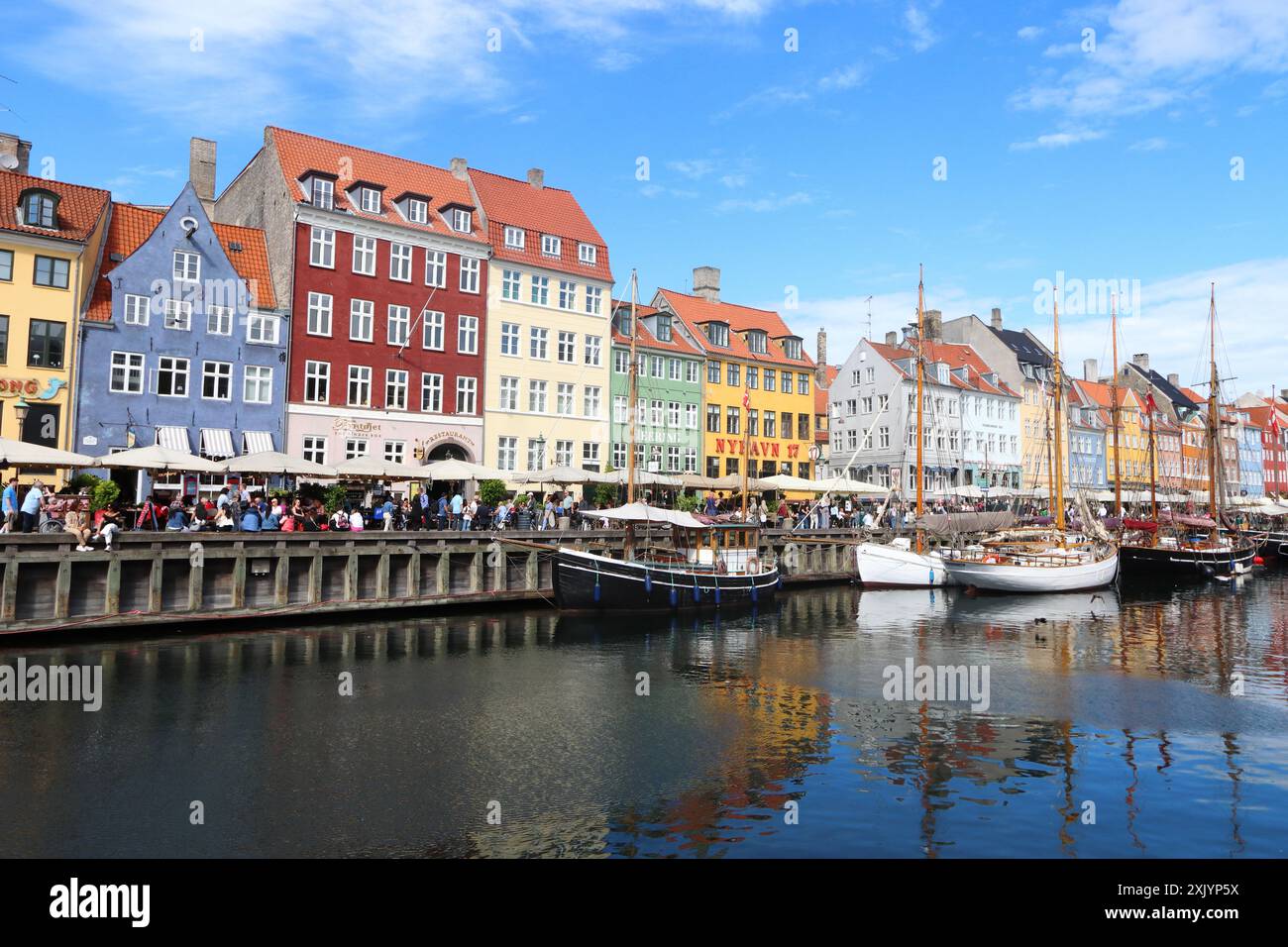 Case e barche colorate, che si riflettono sull'acqua, al porto di Nyhavn a Copenaghen, Danimarca, Europa Foto Stock