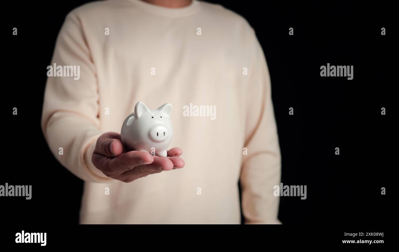 Uomo d'affari che tiene a mano il salvadanaio, risparmia denaro e concetto di crescita degli investimenti, finanza e affari, denaro gestionale. Foto Stock