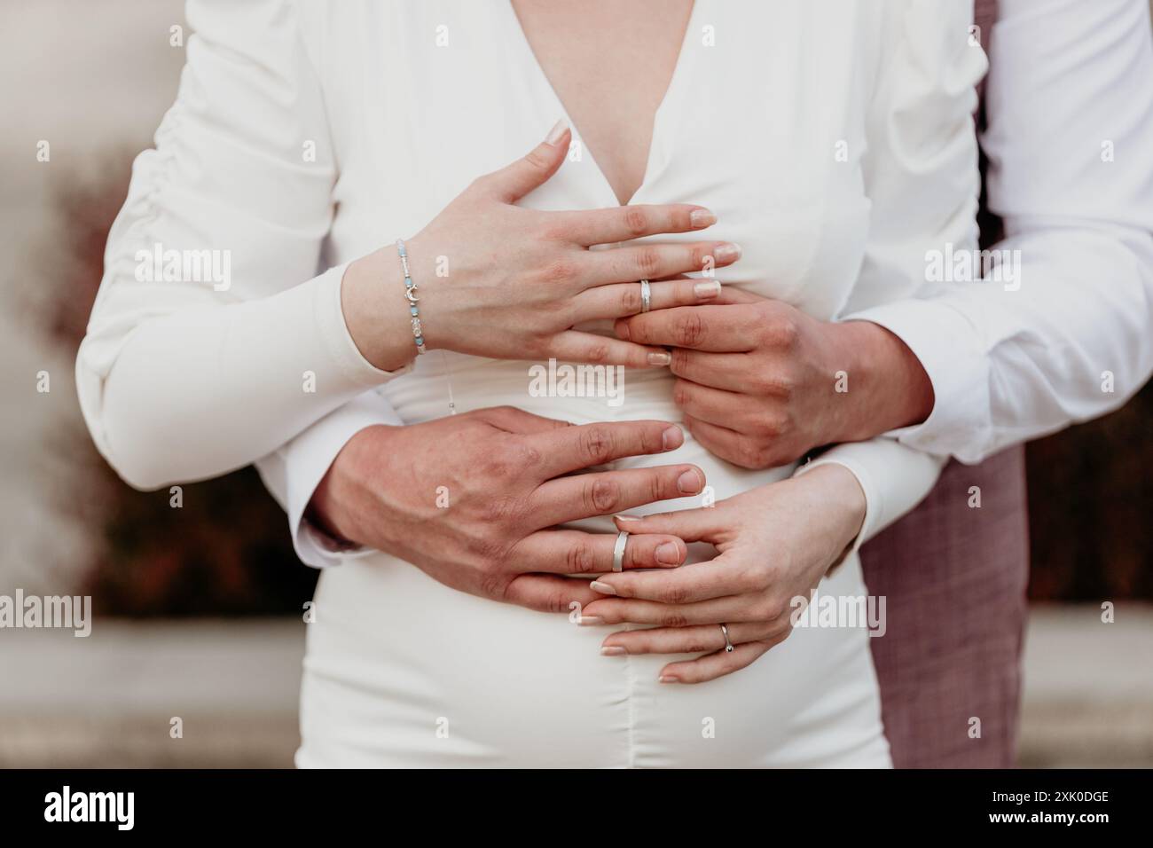 Una coppia appena sposata sta vicino, le loro mani si intrecciano, simboleggiando il loro amore e impegno. Foto Stock