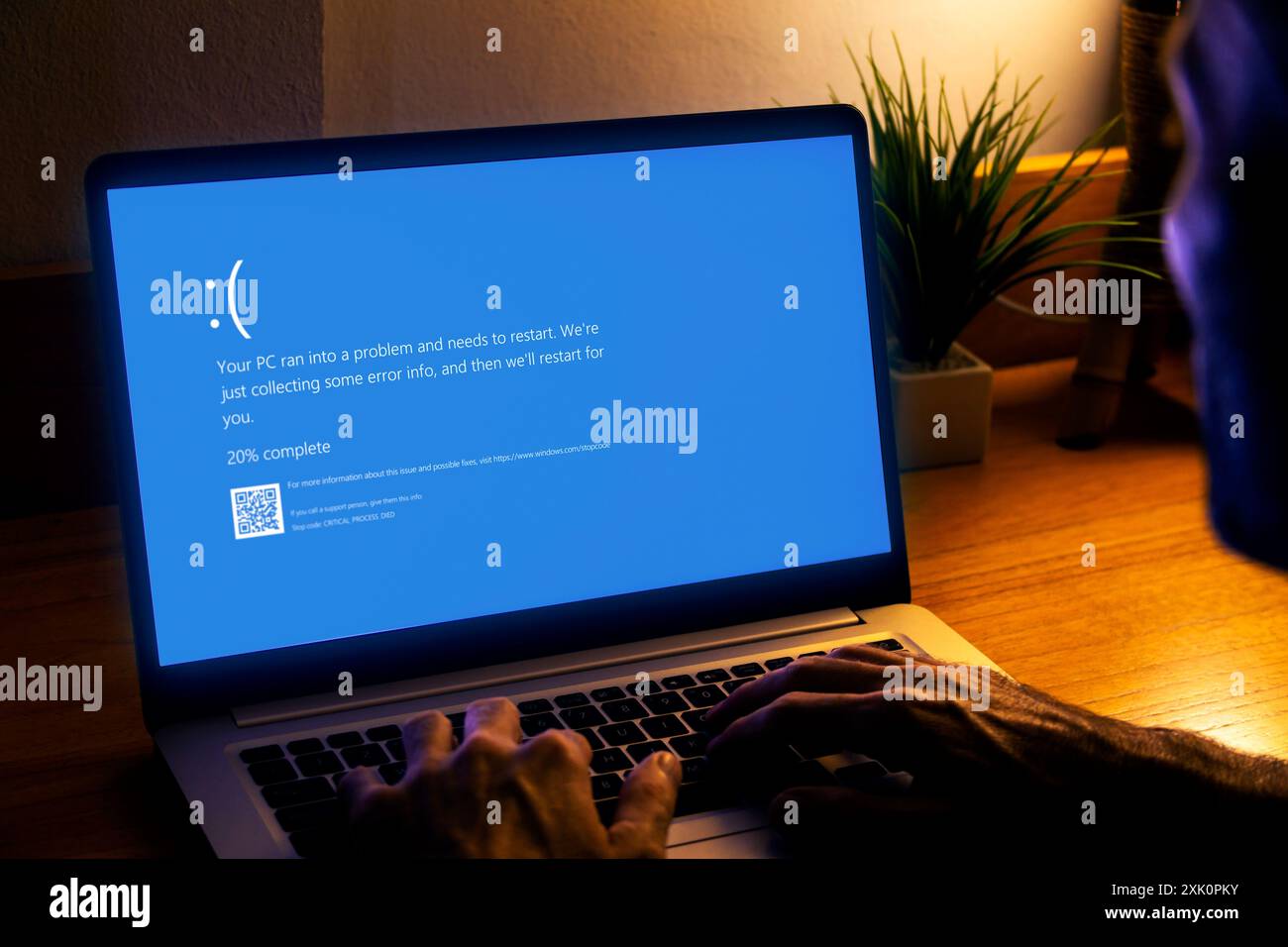 Uomo con notebook che mostra sullo schermo del monitor una schermata blu della morte o BSOD. Sistema operativo Microsoft Windows 10 difettoso. Foto Stock