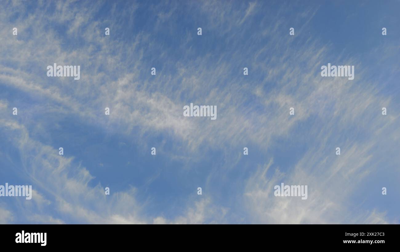 Ampio cielo blu con delicate nuvole bianche, che creano un'atmosfera serena e aperta. Foto Stock