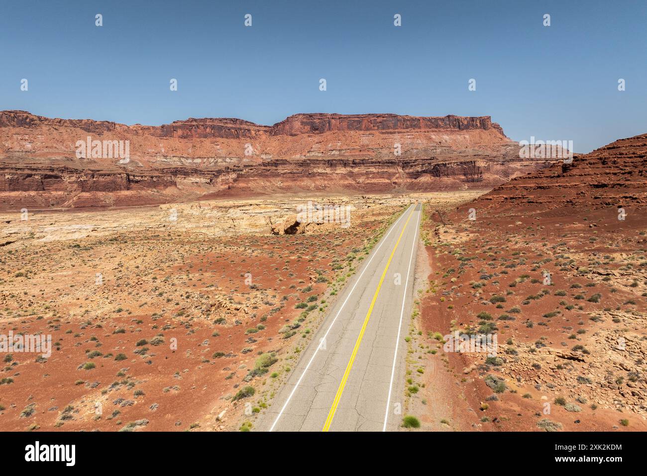 Questa immagine cattura un'autostrada rettilinea che si estende attraverso l'arido paesaggio di rocce rosse del White Canyon nella Glen Canyon National Recreation area, Showca Foto Stock