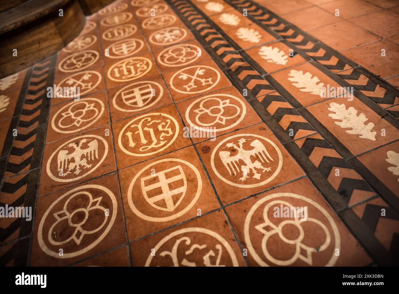 Pavimento della cattedrale di Saint Pierre piastrellato Ginevra Svizzera // GINEVRA, Svizzera — le piastrelle ornate della cattedrale di Saint Pierre mostrano un'elaborata iconografia araldica e elementi simbolici di vari stemmi. Situata nel cuore della città vecchia di Ginevra, la cattedrale presenta una miscela di stili architettonici derivanti dalla sua costruzione che si estende per diversi secoli. La chiesa storica servì come la casa adottiva di Giovanni Calvino, un leader chiave della riforma protestante nel XVI secolo. La cattedrale è un importante punto di riferimento religioso a Ginevra e rappresenta un segno distintivo Foto Stock