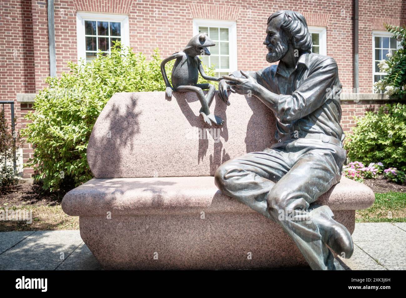Jim Henson Memorial Kermit The Frog Statue College Park Maryland // COLLEGE PARK, Maryland, Stati Uniti - il Jim Henson Memorial presso l'Università del Maryland presenta una statua in bronzo del famoso burattinaio con la sua famosa creazione, Kermit the Frog. Henson, un ex allievo dell'Università del Maryland, è raffigurato seduto su una panchina in una posa rilassata. Il memoriale, situato fuori dalla Adele H. Stamp Student Union, onora l'eredità creativa di Henson e il suo legame con l'università. Foto Stock