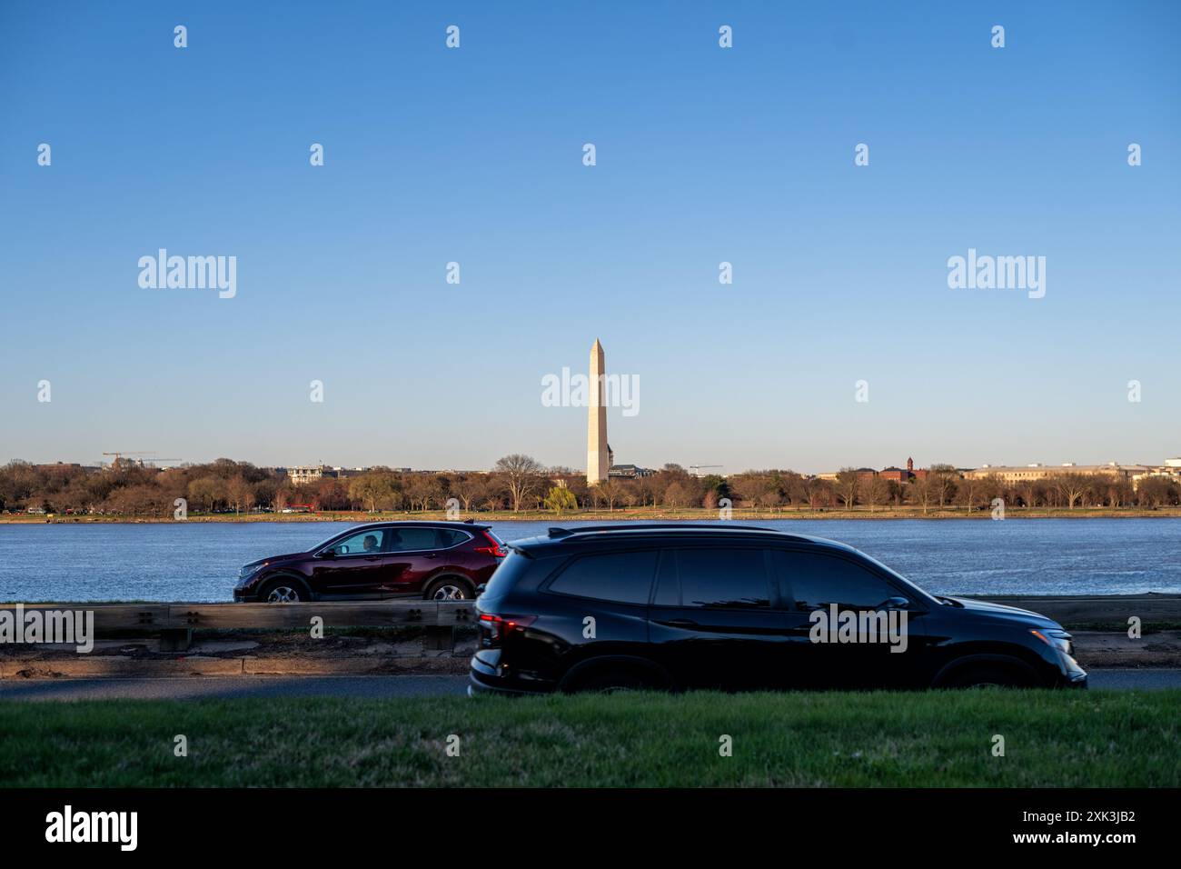 Monumento a Washington dal Lady Bird Johnson Park Washington DC | WASHINGTON DC — Il Monumento a Washington è visto dal Lady Bird Johnson Park, con il fiume Potomac e le auto sulla George Washington Parkway in primo piano. Il parco, intitolato all'ex First Lady, offre viste panoramiche sull'iconico obelisco e sul paesaggio circostante. Il monumento, alto 555 piedi, serve come tributo al primo presidente della nazione, George Washington. Foto Stock